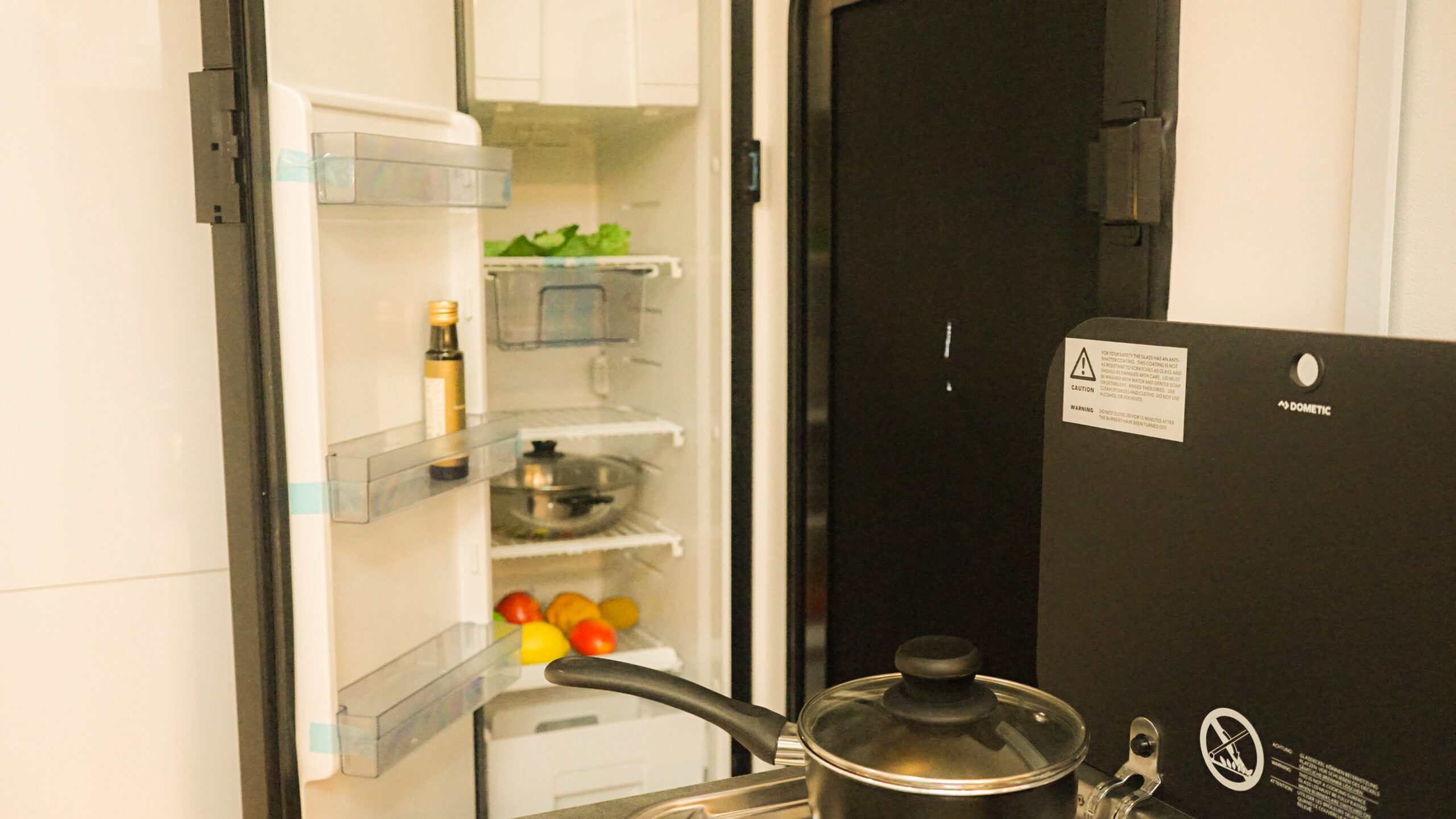 Open refrigerator with fruits, vegetables, and a bottle