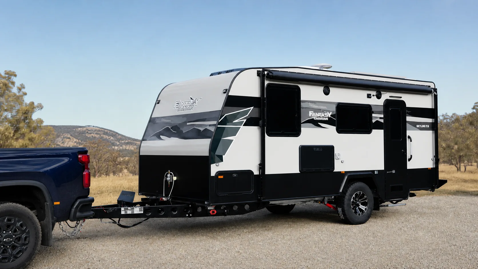 Side view of a Skyline semi off-road caravan hitched to a ute on a gravel clearing