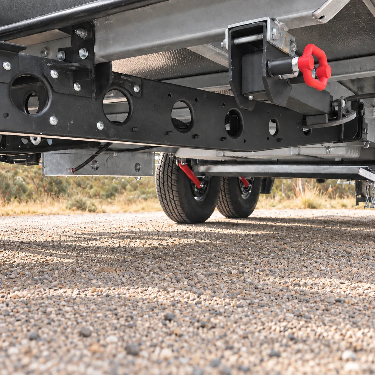 Underside of a Skyline caravan showing the torsion axle suspension above a gravel road
