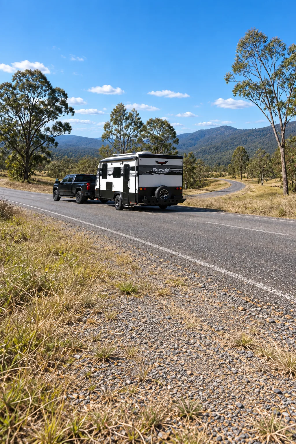 Skyline caravan being towed by a ute along a sealed country road through Australian bushland