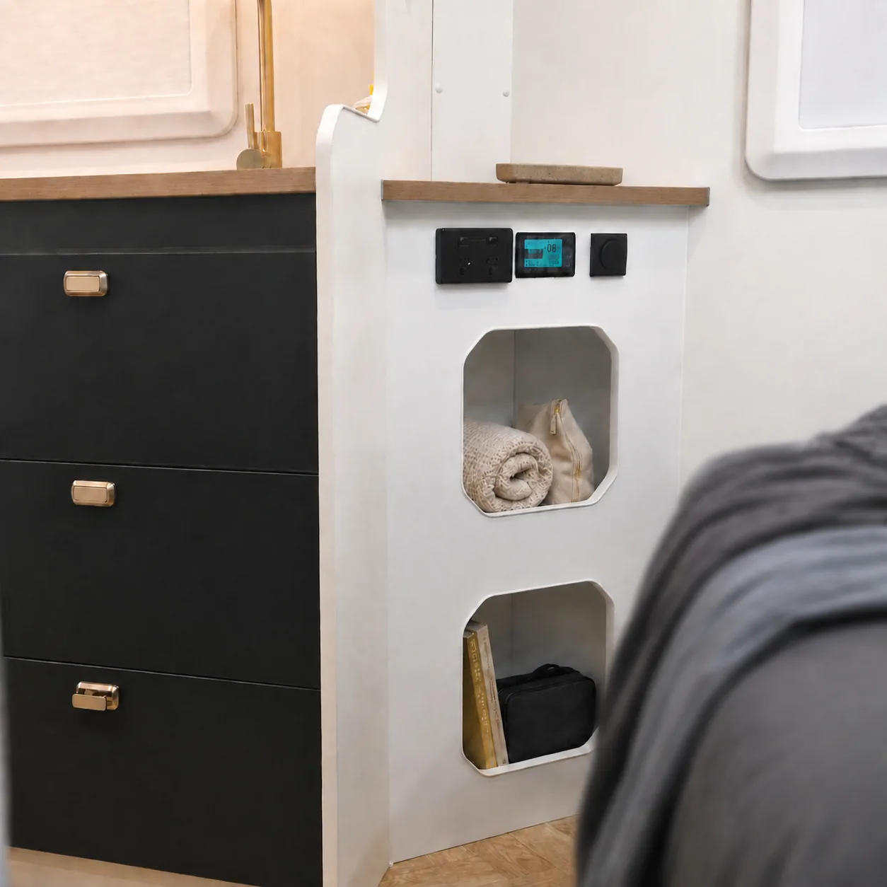 Cabinet drawers and open cubby holes holding towels beside the bed