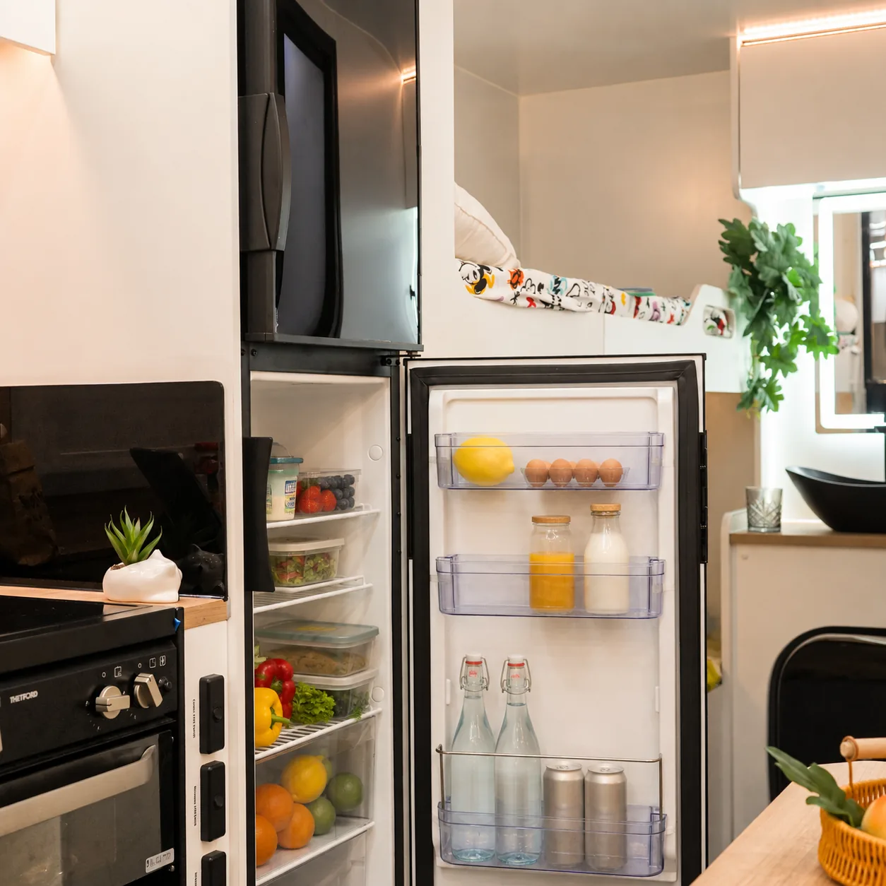 Full-height caravan fridge standing open and stocked with fresh food and drinks