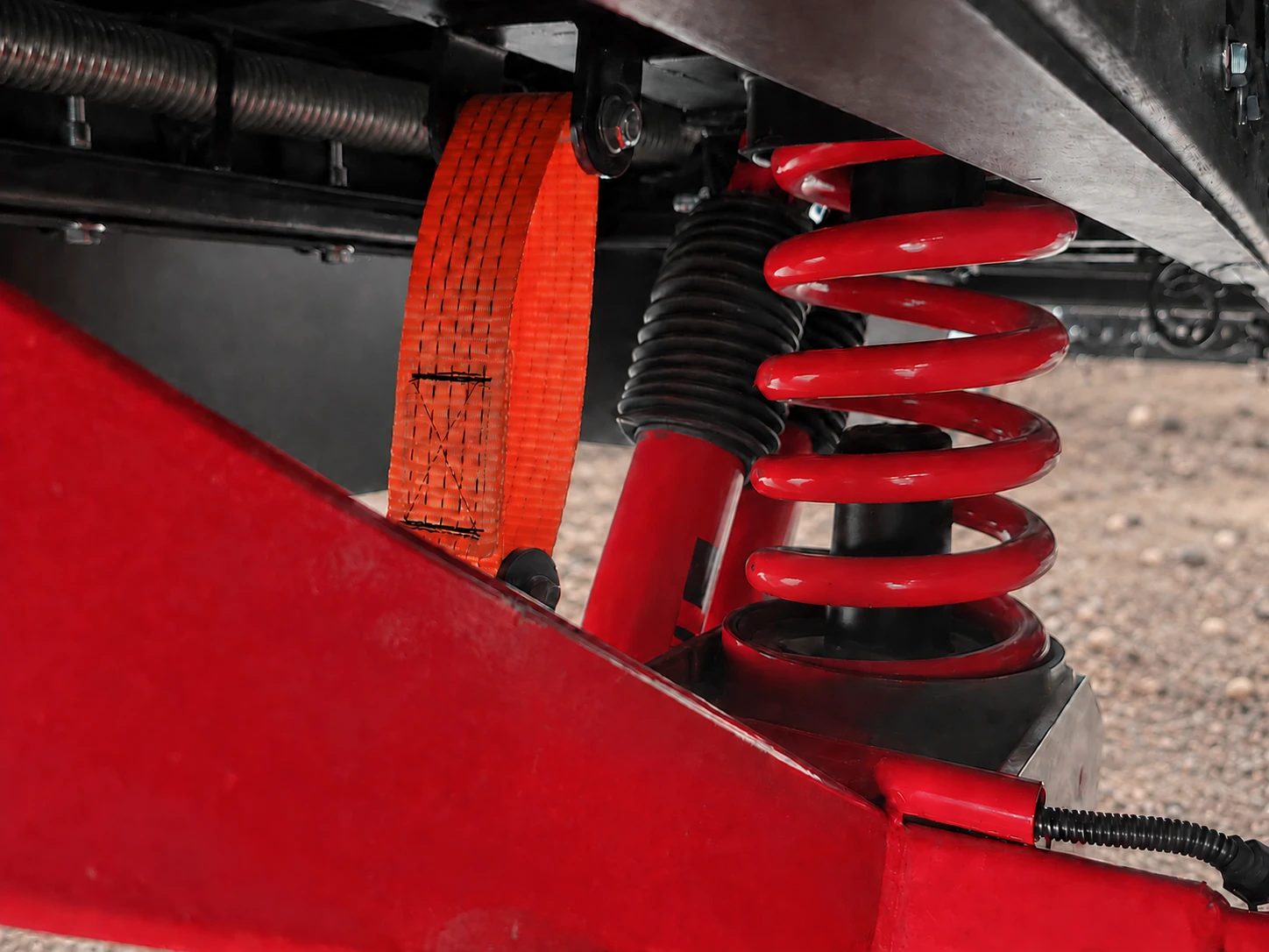 Red coil spring and shock absorber of the Horizon caravan independent suspension, with the suspension arm in the foreground