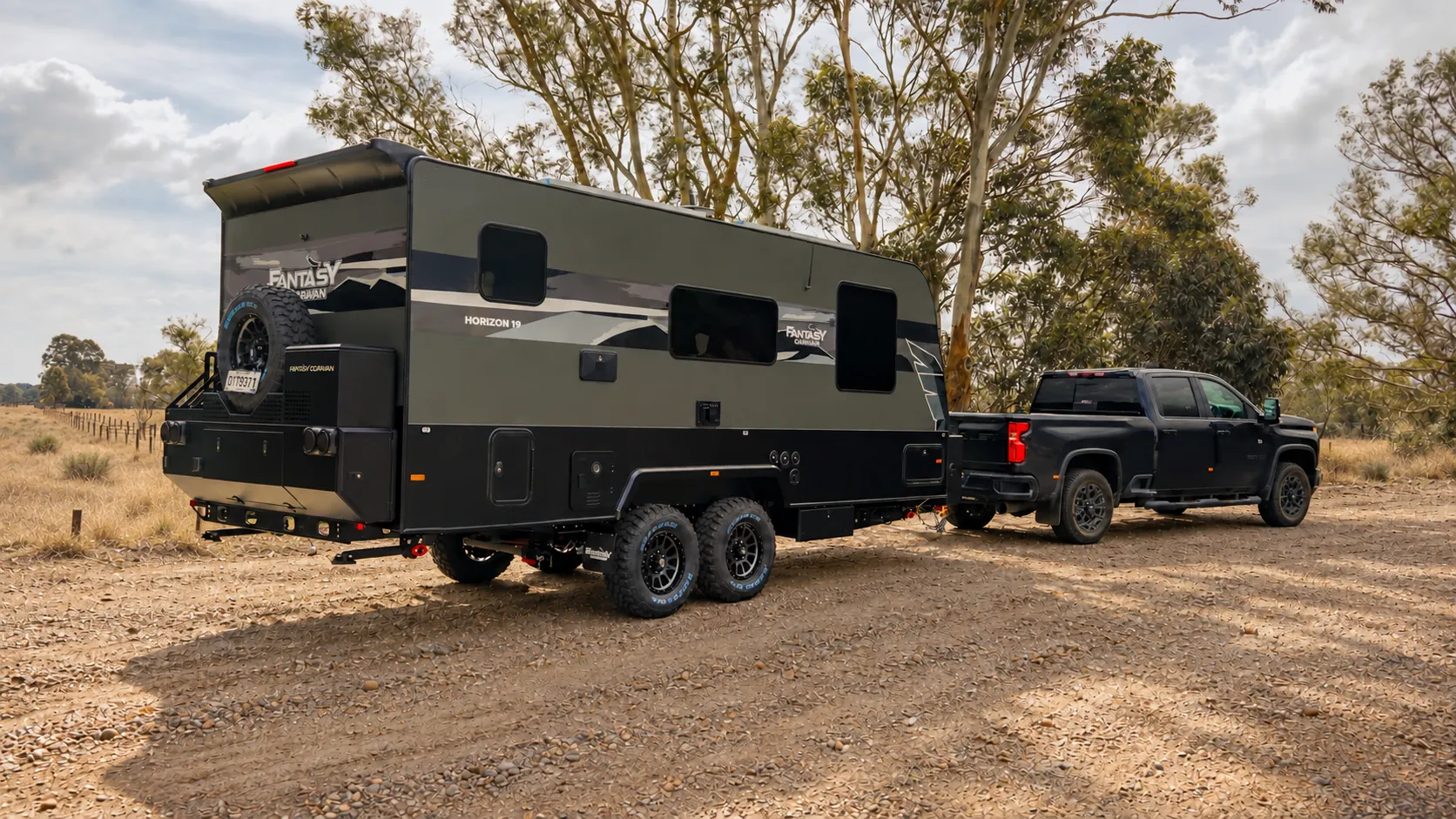 Horizon caravan hitched to a ute at a bush campsite, rear three-quarter view