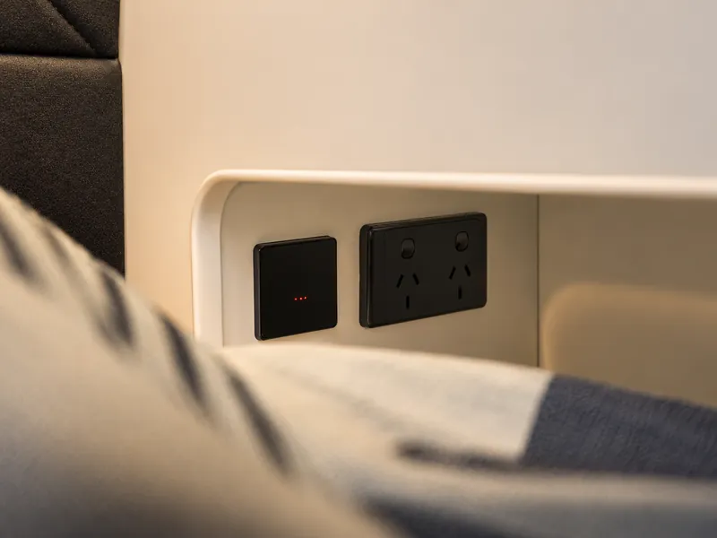 Bedside charging points in a recessed nook beside soft bedding