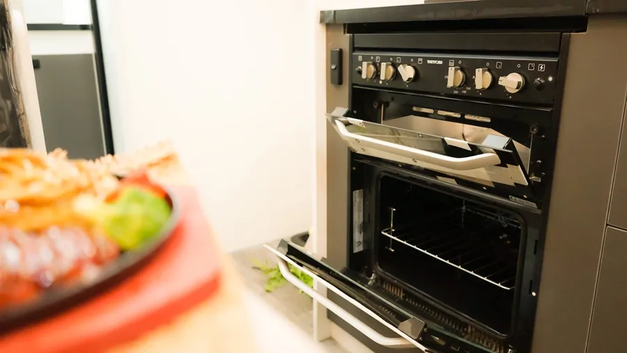 Open grill and oven inside a Horizon caravan with a plated meal in the foreground