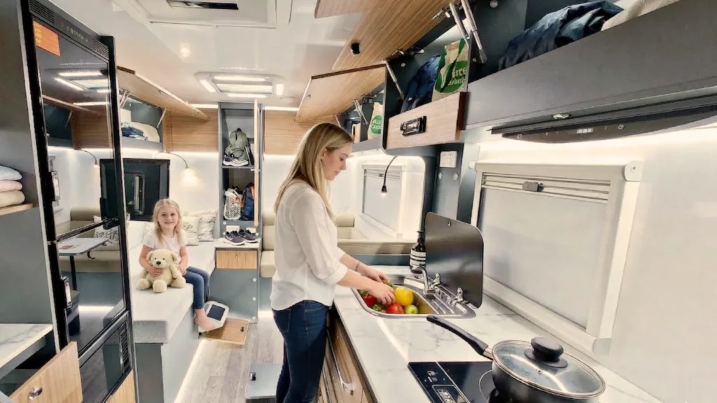 Mother preparing food in a Nano caravan kitchen while her daughter sits at the dinette